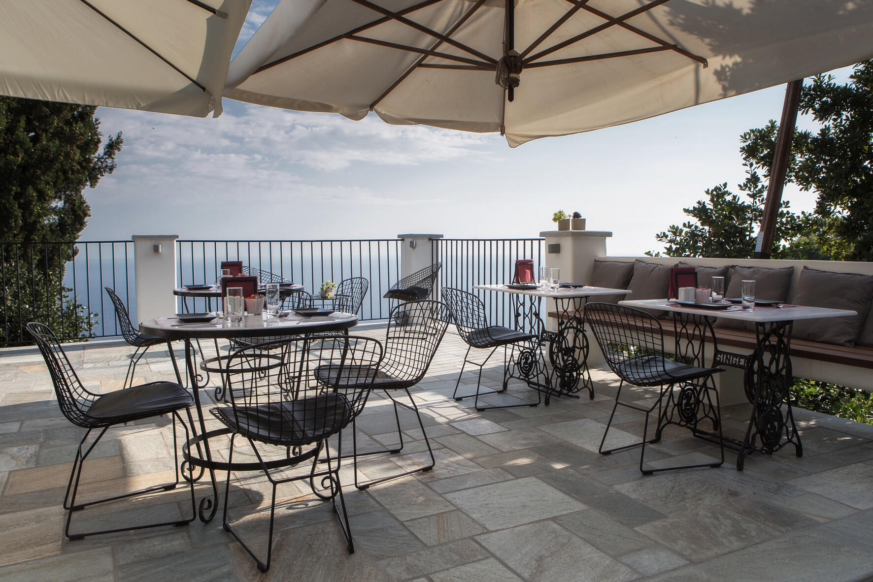 Μοντέρνα ταράτσα με μάρμαρα τραπέζια σε βάση Singer, ενσωματωμένο παγκάκι και πανοραμική θέα στο Αιγαίο. Minimal rooftop featuring marble tables on Singer bases, built-in bench, and serene modern ambiance with panoramic Aegean Sea views.