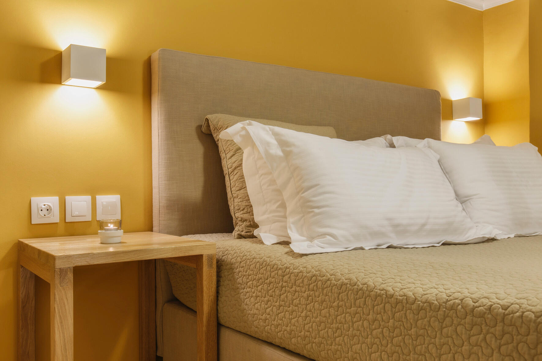 Μοντέρνος εσωτερικός χώρος με λιτές γεωμετρίες και τοίχο σε θερμή κίτρινη απόχρωση. Modern interior with clean geometries and a warm yellow accent wall.