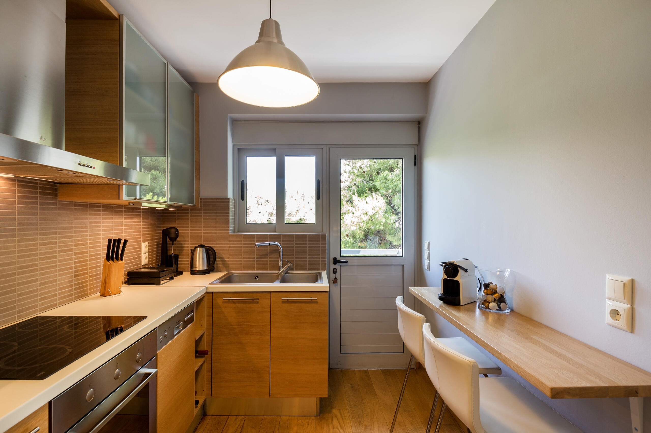 Κουζίνα με επένδυση ξύλου σε φυσικό τόνο και παρκέ ενιαίας ροής σε όλο το διαμέρισμα. Kitchen with natural wood tones and continuous parquet flooring throughout the space.