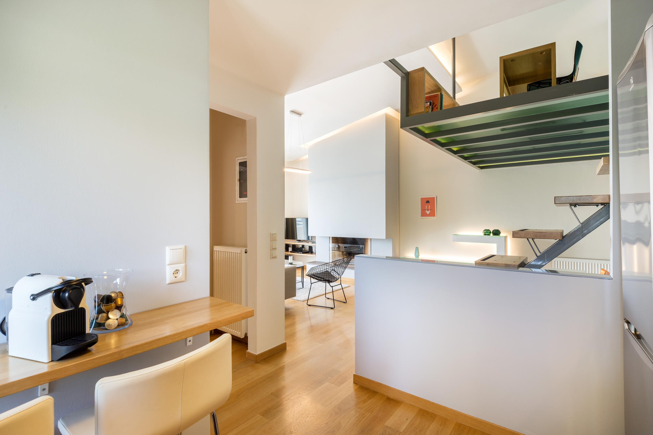 View from the kitchen into a modern office loft with high ceilings, industrial details, and natural light. Θέα από την κουζίνα σε μοντέρνο office loft με ψηλά ταβάνια, industrial λεπτομέρειες και φυσικό φως.